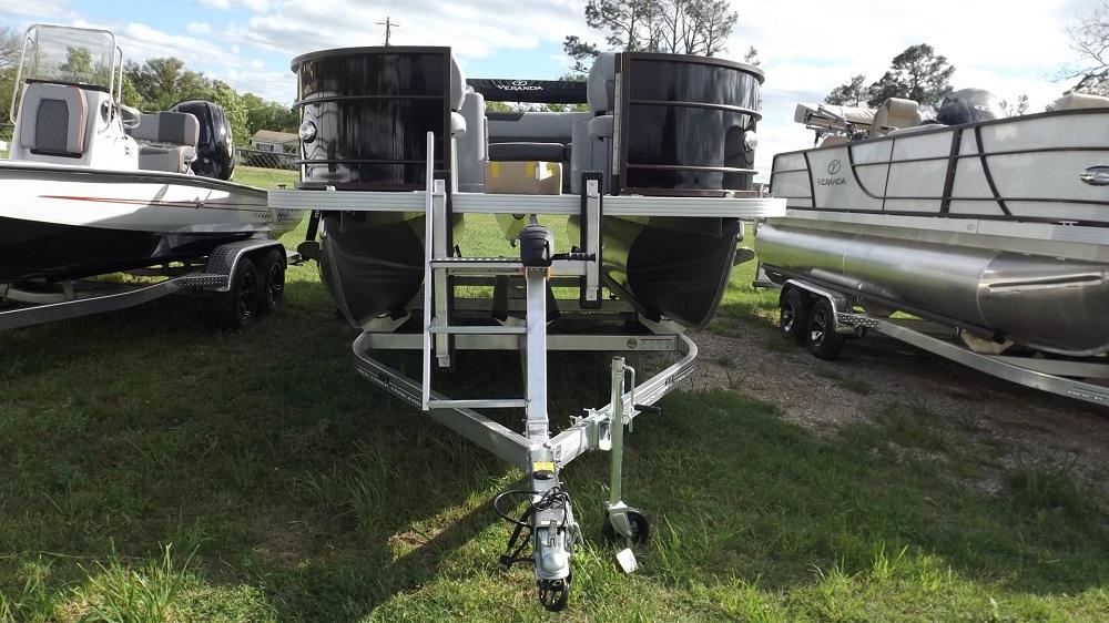 Alt text: "2024 Veranda VF20F4 pontoon boat with dual-hull design on trailer at Lake Fork, flanked by two other boats, under a partly cloudy sky with trees in the background on Sartin Marine's website.