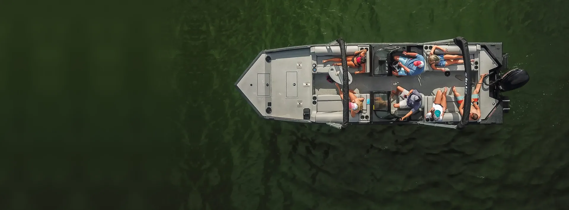 Aerial view of a family on an aluminum fishing boat on green lake water