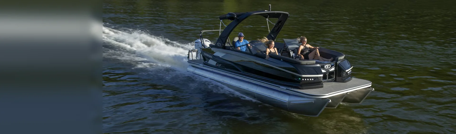 Black and silver pontoon boat running across a lake